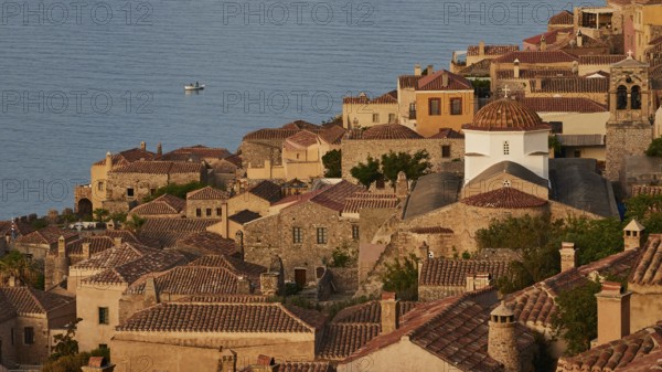 Soft morning light, Holy Church of the Virgin Mary Myrtidiotissa (or Kritikias), view of a historic seaside fishing village with tiled roofs and a small boat in the water, Monemvasia, Monemvassia, Malvasy, Byzantine small town, rocky island, fortress, Laconia, Peloponnese, peninsula, Greece