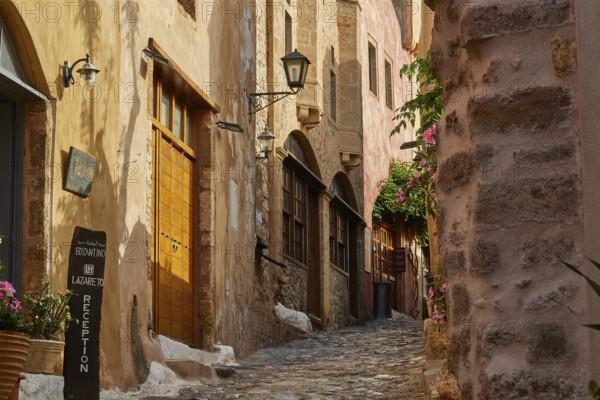 Narrow paved path in the old town with flowering plants and old buildings, Monemvasia, Monemvassia, Malvasy, Byzantine small town, rocky island, fortress, Laconia, Peloponnese, peninsula, Greece