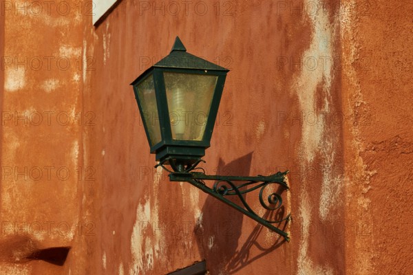 A green lantern hangs on a rust-tinted wall with distinct texture, Monemvasia, Monemvassia, Malvasy, small Byzantine town, rocky island, fortress, Laconia, Peloponnese, peninsula, Greece