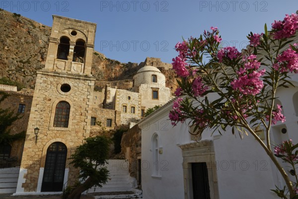 Holy Church of Christ in Chains, Elkomenos Christos, church and tower in front of a rock, with blooming plants in the foreground in the morning light, Monemvassia, Malvasy, small Byzantine town, rocky island, fortress, Laconia, Peloponnese, peninsula, Greece