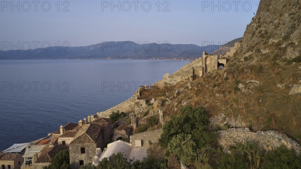 Drone shot, coastal landscape with medieval ruins and view of the blue sea, Monemvasia, Monemvassia, Malvasy, Byzantine small town, rocky island, fortress, Laconia, Peloponnese, peninsula, Greece