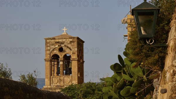 Soft morning light, Holy Church of Christ in Chains, Elkomenos Christos, bell tower with cross next to an old stone wall under a blue sky, surrounded by greenery, Monemvassia, Malvasy, small Byzantine town, rocky island, fortress, Laconia, Peloponnese, peninsula, Greece