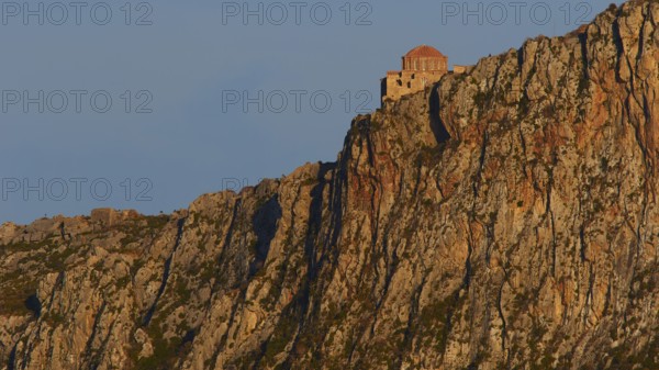 Orhodox church of Hagia Sophia, secluded monastery buildings on rough rocks, illuminated by the evening sun, Monemvassia, Malvasy, small Byzantine town, rocky island, fortress, Laconia, Peloponnese, peninsula, Greece