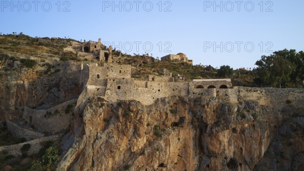 Mighty castle perched over rocky landscape under clear sky, Monemvasia, Monemvassia, Malvasy, Byzantine small town, rocky island, fortress, Laconia, Peloponnese, peninsula, Greece