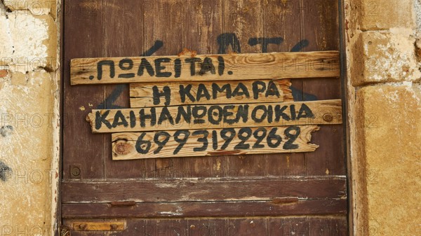 Old wooden door with Greek writing fixed on wooden slats, Monemvasia, Monemvassia, Malvasy, small Byzantine town, rocky island, fortress, Laconia, Peloponnese, peninsula, Greece