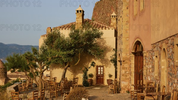Soft morning light, cozy open-air café with rustic charm and historic buildings at sunrise, Monemvasia, Monemvassia, Malvasy, small Byzantine town, rocky island, fortress, Laconia, Peloponnese, peninsula, Greece