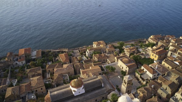Drone shooting Sacred Church of Christ in Chains, Elkomenos Christos, Holy Church of the Virgin Mary Myrtidiotissa (or Critikias), drone shot, bird's eye view of a coastal village with traditional buildings and extensive sea views, Monemvassia, Malvasy, Byzantine small town, rocky island, fortress, Laconia, Peloponnese, peninsula, Greece