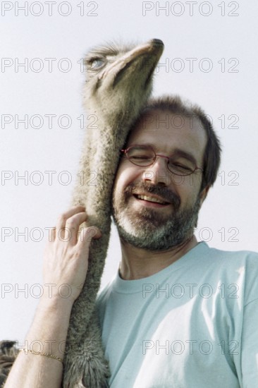 DEU, Mannheim, 22.07.1994 -- ostrich breeder (man, hug, bird ostrich, stroking, affection) -- © Karsten Thielker
