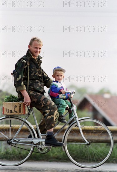BIH, Bosnia, Tuzla, 23.08.1994 A Bosnian soldier rides a bicycle with his son