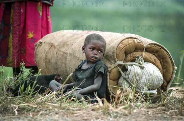 TZA Tanzania scene in the Benaco Camp refugee camp, to which up to 500, 000 Rwandan Tutsis fled the genocide in their country. Refugee child is leaning on a mattress next to a chicken. TZA Tanzania Scene at the Benaco Camp, where an estimate of 500, 000 Rwandan Tutsi refugees fled the genocide in their country. Refugee Kid Rests Next to a Mattress