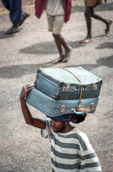 TZA Tanzania scene in the Benaco Camp refugee camp, to which up to 500, 000 Rwandan Tutsis fled the genocide in their country. A refugee carries two suitcases on his head. TZA Tanzania Scene at the Benaco Camp, where an estimate of 500, 000 Rwandan Tutsi refugees fled the genocide in their country. A man carries two suitcases on his head