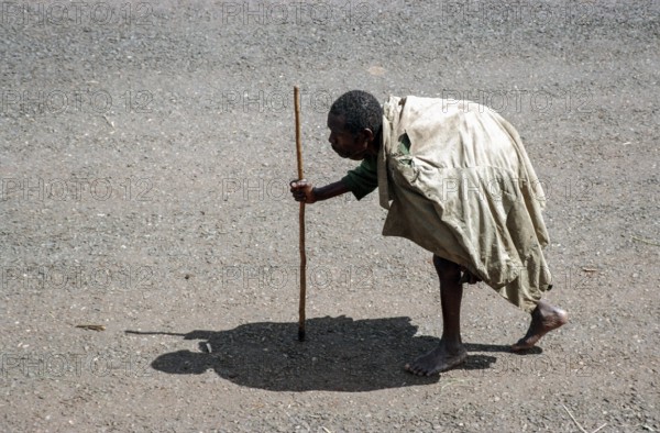 TZA Tanzania scene in the Benaco Camp refugee camp, to which up to 500, 000 Rwandan Tutsis fled the genocide in their country. The shadow of an old man with a stick resembles the stature of a Maasai warrior. TZA Tanzania Scene at the Benaco Camp, where an estimate of 500, 000 Rwandan Tutsi refugees fled the genocide in their country. The Shadow of a Man with a Walking Stick looks like the Statue of a Maasai Warrior