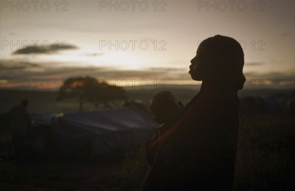 TZA Tanzania scene in the Benaco Camp refugee camp, to which up to 500, 000 Rwandan Tutsis fled the genocide in their country. Woman with toddler early in the morning. TZA Tanzania Scene at the Benaco Camp, where an estimate of 500, 000 Rwandan Tutsi refugees fled the genocide in their country. Women and her child in the early morning hours