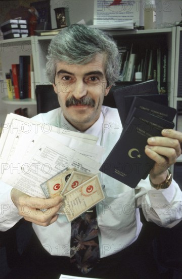 Berlin, DEU, 10.11.1998 -- portrait of Diyap Sarkalli holding Turkish passports and other documents. (bureaucracy, personal details) -- © Karsten Thielker