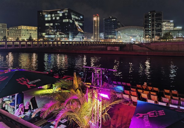 Nightlife on Ludwig-Erhard-Ufer in an outdoor restaurant with the Spree and Berlin Central Station at night, Berlin, Germany