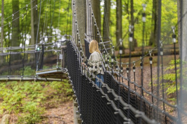 Woman walking on a sturdy rope bridge through the forest, Treewalk, Affenberg Salem, Bodenseekreis, Germany