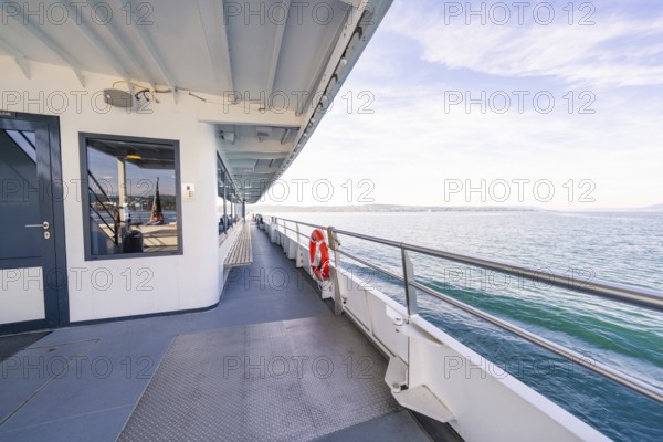 Side of a ship with lifebuoy, looking out over the sea on a clear blue day, boat trip, Lake Constance, Germany