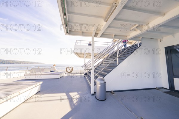 An upper deck of a modern ship with seats and a view of the sea under a blue sky, Schiff Fahrt, Lake Constance, Germany