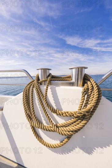Thick ropes carefully draped on the boat deck in front of a wide sky and sea view, boat trip, Lake Constance, Germany