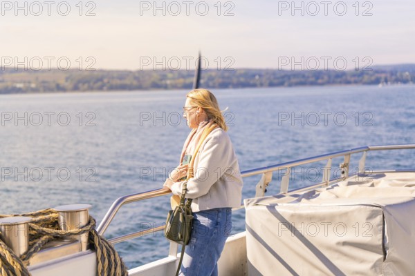 Woman leaning calmly on the railing with a view of the vast water landscape, boat trip, Lake Constance, Germany