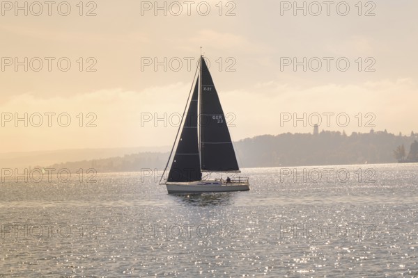 Sailing boat with black sails peacefully across the sparkling lake, boat trip, Lake Constance, Germany