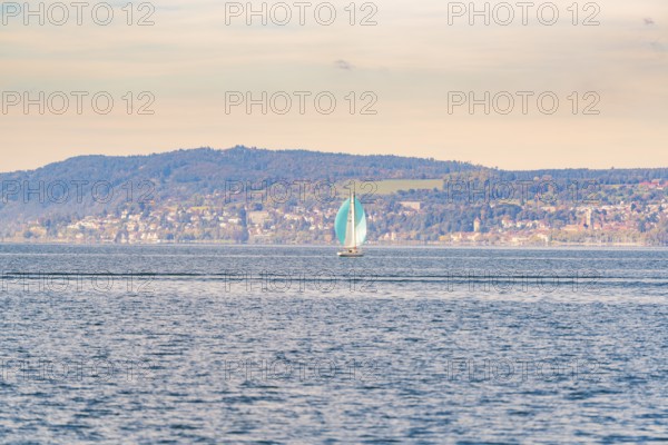 Single sailboat on open water in front of a hilly landscape, boat trip, Lake Constance, Germany