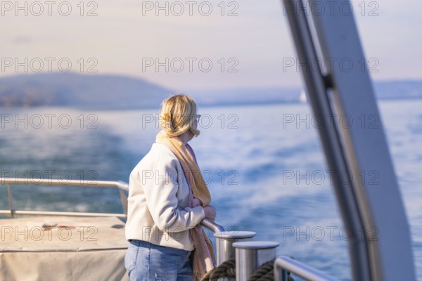 Woman looking relaxed from the ship at the calm water under a blue sky, Schiff Fahrt, Lake Constance, Germany