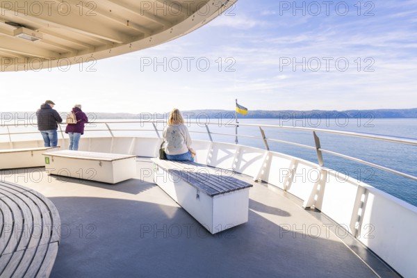 Passengers enjoy the view from a ferry in clear weather, Schiff Fahrt, Lake Constance, Germany