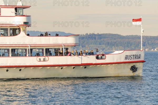 Ship with Austrian flag on calm water with landscape background, boat trip, Lake Constance, Germany