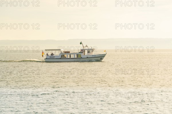 A small boat sails quietly across a lake with gentle waves to the horizon, boat trip, Lake Constance, Germany