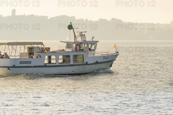 Small boat on a quiet lake near the coast with parasol and flag, boat trip, Lake Constance, Germany