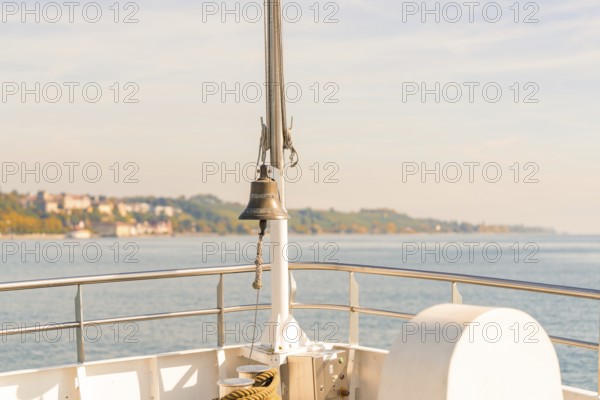 View of the water from a ship with a railing and a bell in the foreground, Schiff Fahrt, Lake Constance, Germany
