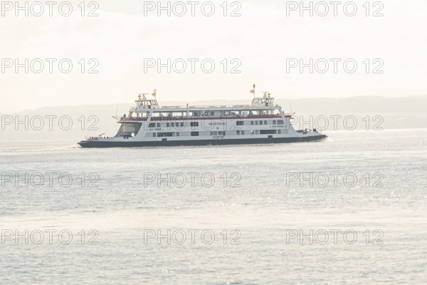 Ferry sails on a calm lake under a pastel colored sky, boat trip, Lake Constance, Germany