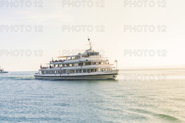 A large ship sails across a sunny lake with a warm glow of light, boat trip, Lake Constance, Germany