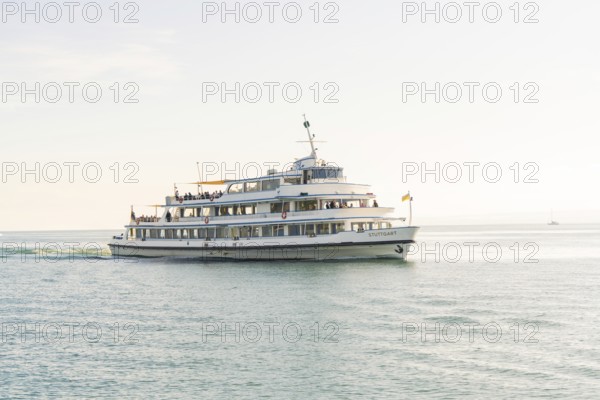 A white passenger liner sails across a still lake under a clear sky, boat trip, Lake Constance, Germany