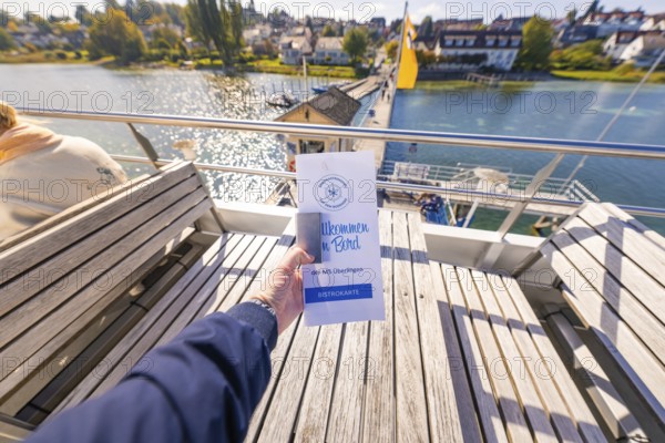 Brochure is being held on a ship heading towards the pier, Schiff Fahrt, Lake Constance, Germany