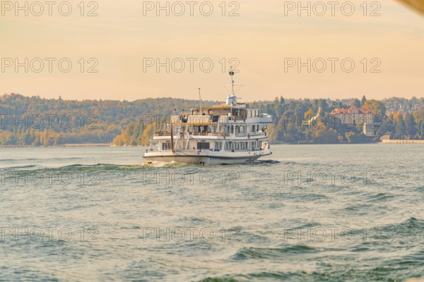 A passenger ship glides on a lake along an autumnal coastal landscape, boat trip, Lake Constance, Germany