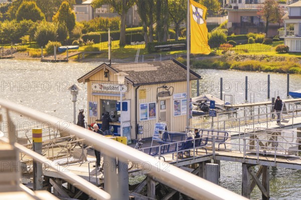 Jetty with buildings in the background under autumn sun, boat trip, Lake Constance, Germany