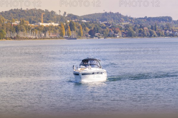 Motor boat rides on a quiet lake with wooded shore, boat trip, Lake Constance, Germany