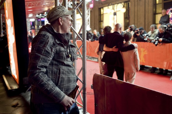 DEU, Germany, Berlin Man with beer in hand watches the hustle and bustle on the red carpet in front of the Friedrichsstadt Palace. Germany Berlin Man with Beer in His Hand Watches a Shooting on the Red Carpet Outside Friedrichsstadt Palace
