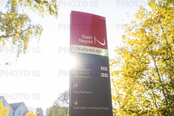 Signpost in Stadtpark Nagold, flooded with sunlight, surrounded by autumn trees, Nagold, Black Forest, Germany