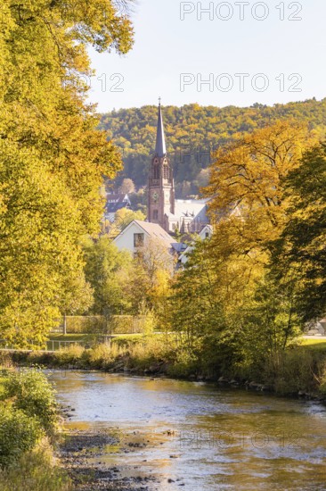 River landscape with a view of a church and autumn trees in a small village, Nagold, Black Forest, Germany