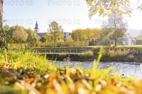 Idyllic river course in autumn with view of a church and colorful trees, Nagold, Black Forest, Germany