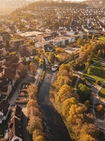 A river flows through an autumnal urban landscape, surrounded by parks and colorful trees, Nagold, Black Forest, Germany