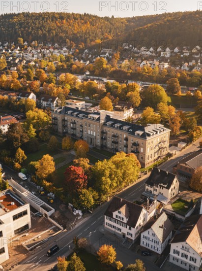 Autumn view from above of a city surrounded by trees and hills, in warm sunlight, Nagold, Black Forest, Germany