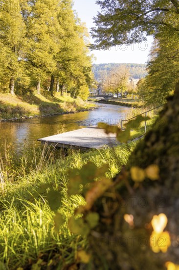 View across the river onto a jetty, captured in golden autumn light, Nagold, Black Forest, Germany
