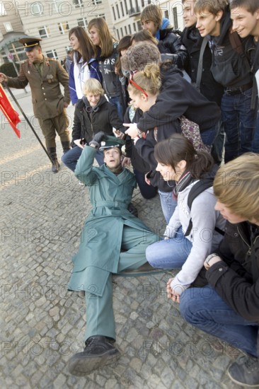 DEU Berlin A man disguised as a GDR soldier during a group photo in front of the Brandenburg Gate. Germany Berlin Family Picture with an Actor, Dress in GDR Army Uniform, at Brandenburg Gate