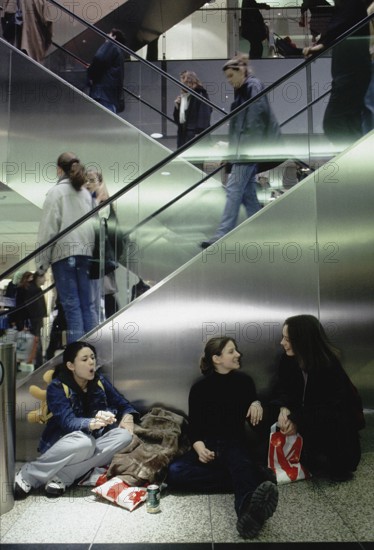 Berlin, DEU, 12.09.1999 -- Young visitors to the Potsdamer Platz arcades take a cigarette break. (escalator, shopping center, people, girls, smoking) -- Â© Karsten Thielker