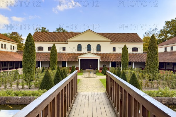 View from site of archaeological open-air museum across small wooden bridge across ornamental pond to reconstructed main building Manor House of Archaeological Park Römische Villa Borg, Perl, Saarland, Germany