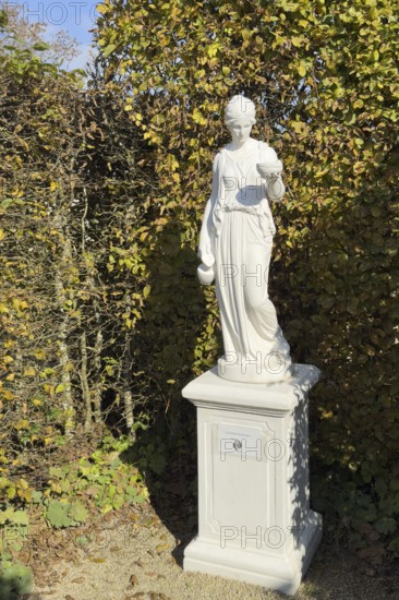 Statue of in Greek mythology goddess of youth Hebe Roman goddess Iuventas of male youth holding a sacrificial bowl in the garden of the open-air museum archaeological park Römische Villa Borg, Perl, Saarland, Germany